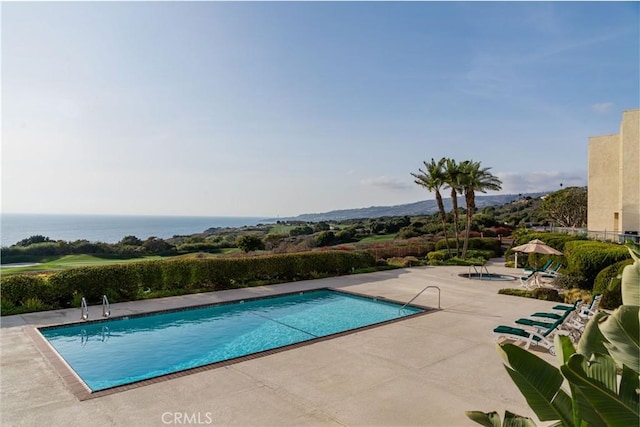 view of swimming pool with a patio and a water view