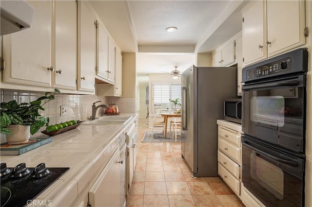 kitchen with tasteful backsplash, sink, tile counters, ceiling fan, and black appliances