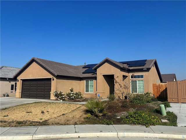 single story home with a garage and solar panels