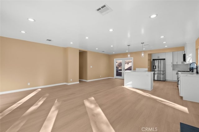 kitchen featuring pendant lighting, white cabinetry, a center island, stainless steel refrigerator with ice dispenser, and light hardwood / wood-style floors