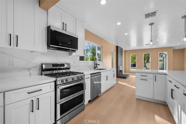 kitchen featuring white cabinetry, sink, pendant lighting, and stainless steel appliances