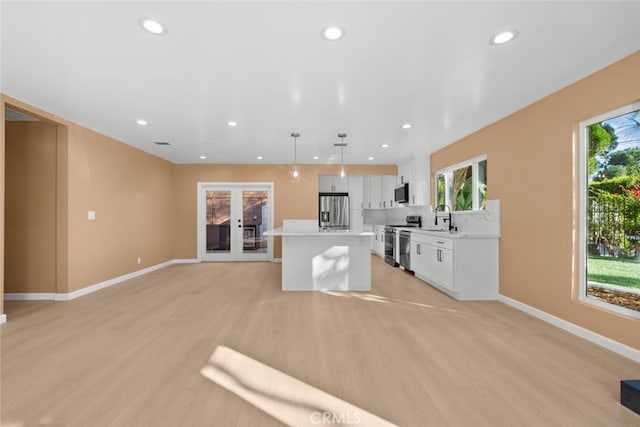 kitchen featuring appliances with stainless steel finishes, sink, white cabinets, hanging light fixtures, and a center island