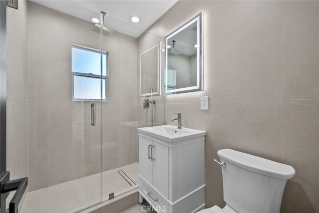 bathroom featuring vanity, toilet, tile walls, and walk in shower