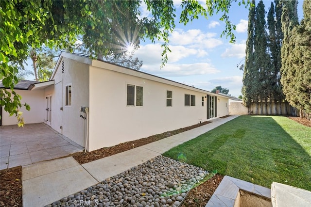 view of side of property featuring a patio area and a lawn