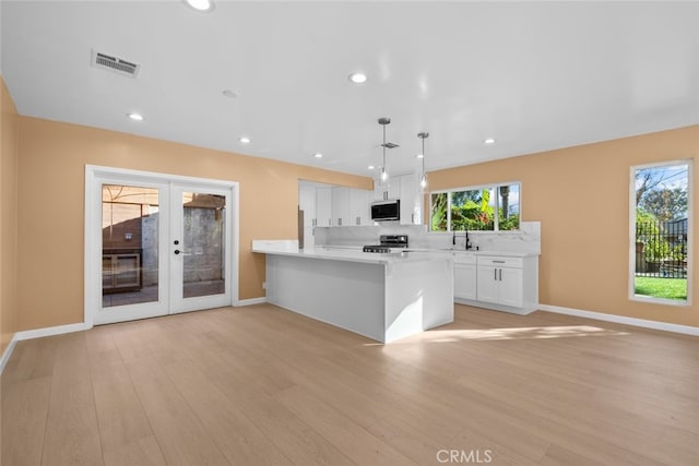 kitchen featuring french doors, white cabinets, pendant lighting, light hardwood / wood-style floors, and stove