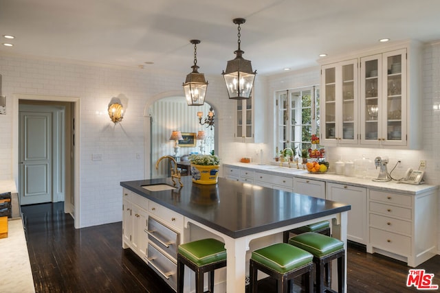 kitchen with pendant lighting, sink, white cabinets, a center island with sink, and dark hardwood / wood-style flooring