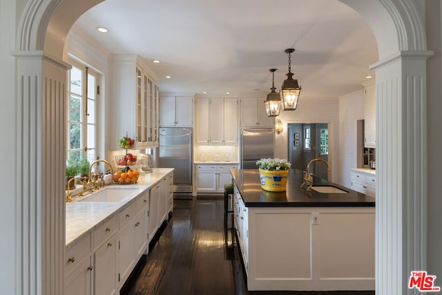 kitchen featuring an island with sink, stainless steel built in refrigerator, and sink