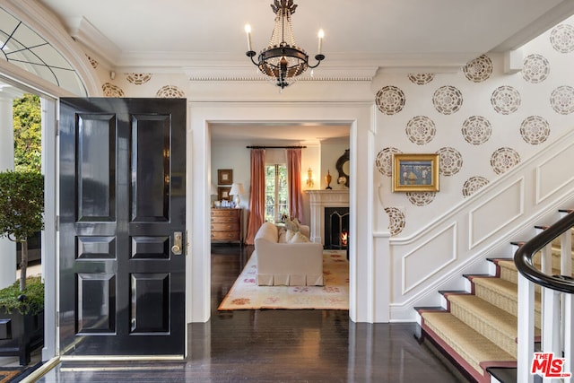 entryway with crown molding, dark hardwood / wood-style flooring, and a chandelier