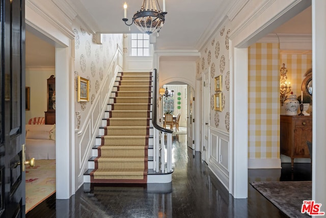 foyer with an inviting chandelier, dark hardwood / wood-style floors, and crown molding