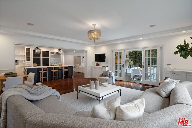 living room featuring french doors, ornamental molding, dark hardwood / wood-style flooring, and a chandelier