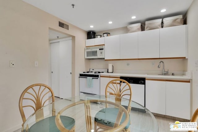 kitchen with white cabinetry, sink, and white appliances