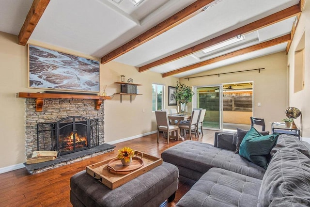 living room featuring lofted ceiling with beams, wood-type flooring, and a stone fireplace