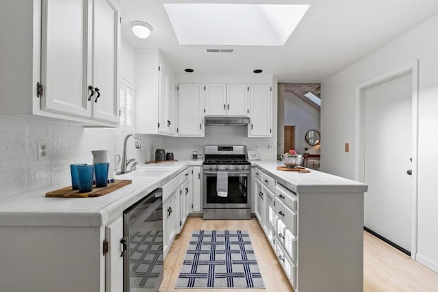 kitchen with sink, stainless steel range with gas cooktop, dishwasher, kitchen peninsula, and white cabinets