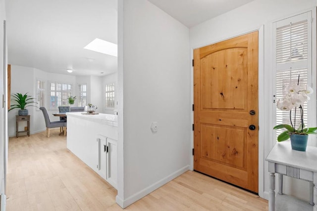 entryway with light hardwood / wood-style flooring and a skylight