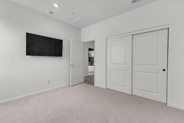 unfurnished bedroom featuring light carpet and a closet