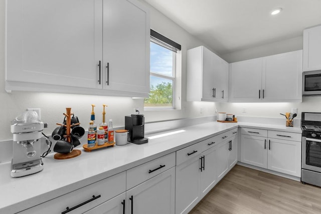 kitchen with stainless steel appliances, light wood-type flooring, and white cabinets