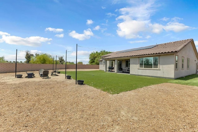 back of property featuring a patio, a lawn, and an outdoor fire pit