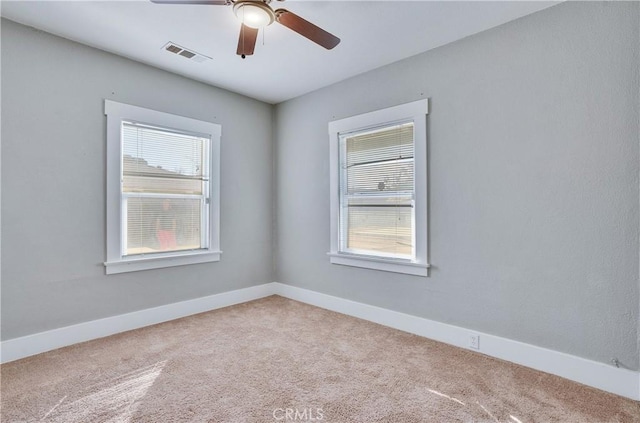 carpeted empty room featuring a healthy amount of sunlight and ceiling fan