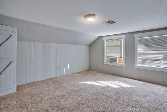 additional living space with cooling unit, lofted ceiling, and carpet floors