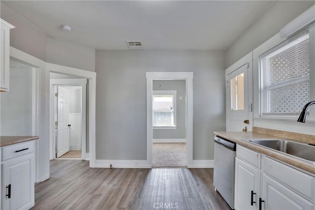 kitchen with white cabinetry, sink, stainless steel dishwasher, and light hardwood / wood-style floors