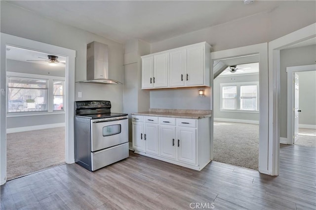 kitchen with white cabinetry, wall chimney exhaust hood, light carpet, and stainless steel range with electric cooktop