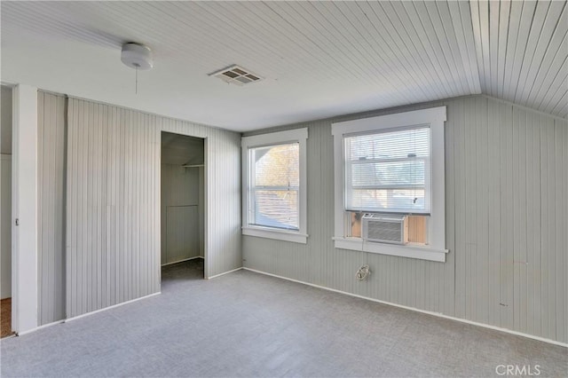 unfurnished bedroom with cooling unit, vaulted ceiling, light colored carpet, and a closet