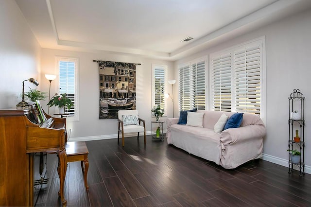 living room featuring plenty of natural light, dark hardwood / wood-style floors, and a tray ceiling