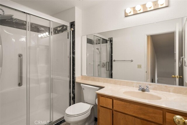 bathroom with vanity, a shower with shower door, and toilet