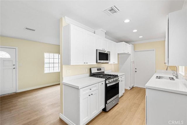 kitchen with appliances with stainless steel finishes, sink, light hardwood / wood-style flooring, and white cabinets