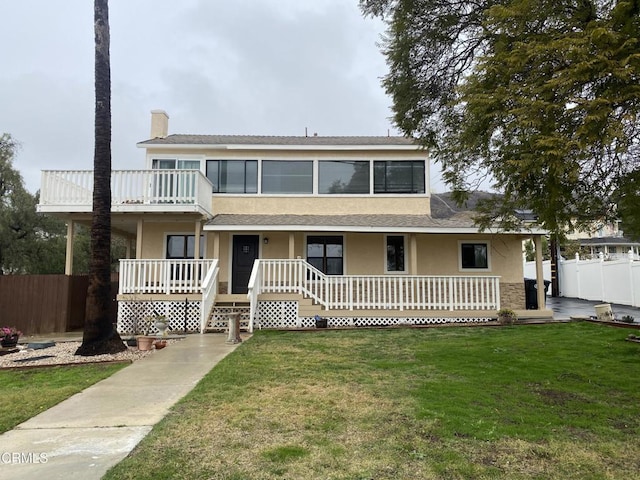 view of front of property with a front yard, a balcony, and a porch