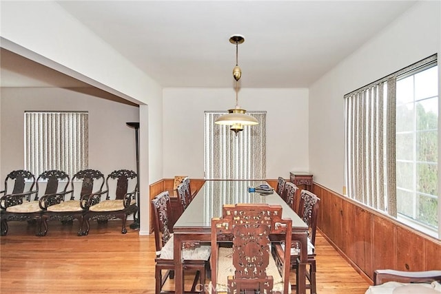 dining room featuring light hardwood / wood-style floors and wood walls