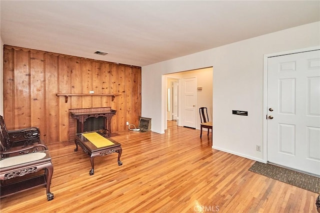 living area with wooden walls, a fireplace, and light wood-type flooring