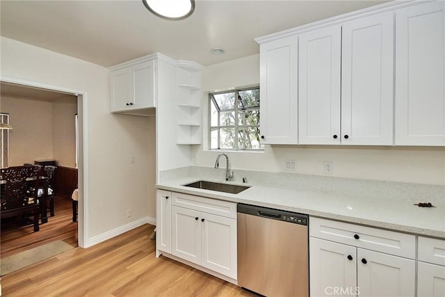 kitchen with white cabinetry, sink, stainless steel dishwasher, light hardwood / wood-style floors, and light stone countertops