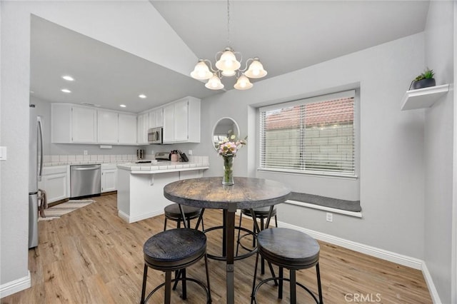 dining room with vaulted ceiling, light hardwood / wood-style floors, and a chandelier