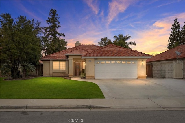 mediterranean / spanish house featuring a garage and a yard