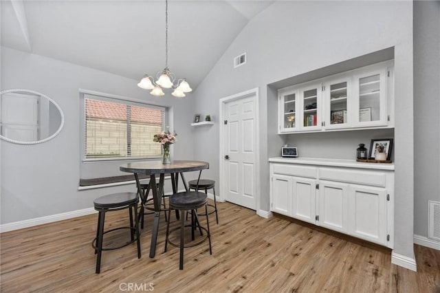 dining space featuring vaulted ceiling, light hardwood / wood-style floors, and a notable chandelier