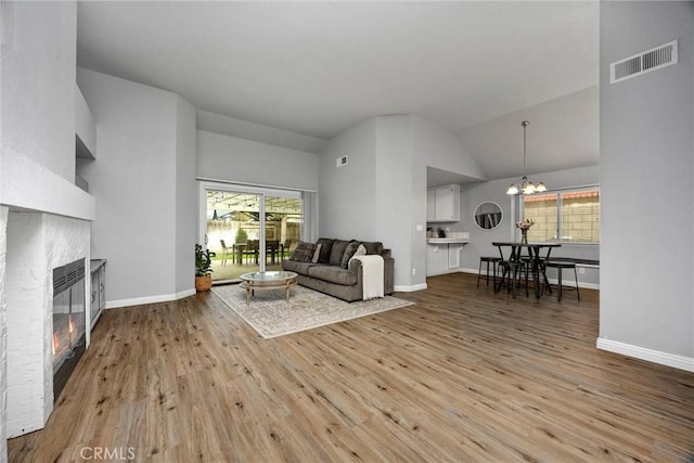 living room featuring lofted ceiling, a chandelier, and light wood-type flooring