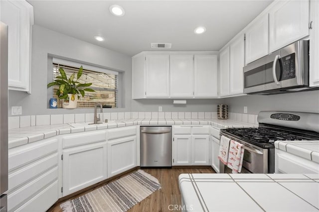 kitchen featuring white cabinetry, appliances with stainless steel finishes, and tile countertops