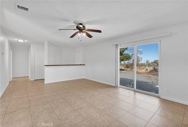 tiled empty room featuring ceiling fan and a textured ceiling