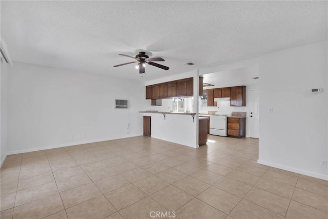 kitchen featuring light tile patterned floors, ceiling fan, a textured ceiling, a kitchen bar, and white gas range