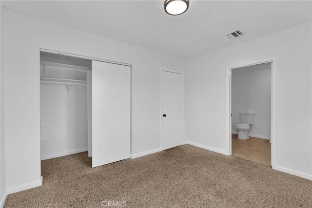 unfurnished bedroom featuring ensuite bathroom, a closet, and carpet