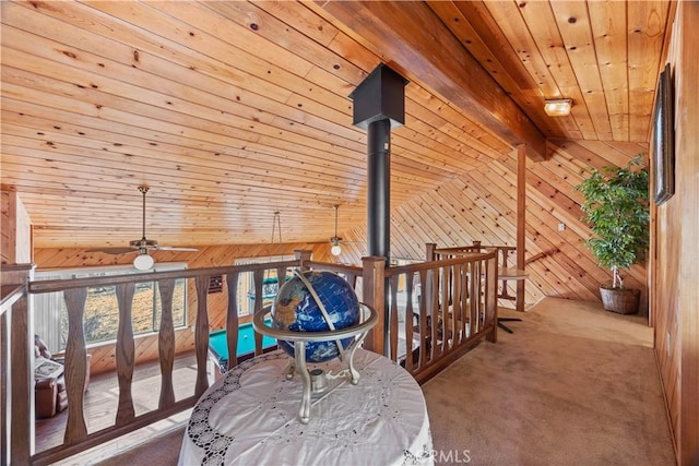 interior space with wood ceiling, ceiling fan, vaulted ceiling with beams, carpet, and wood walls