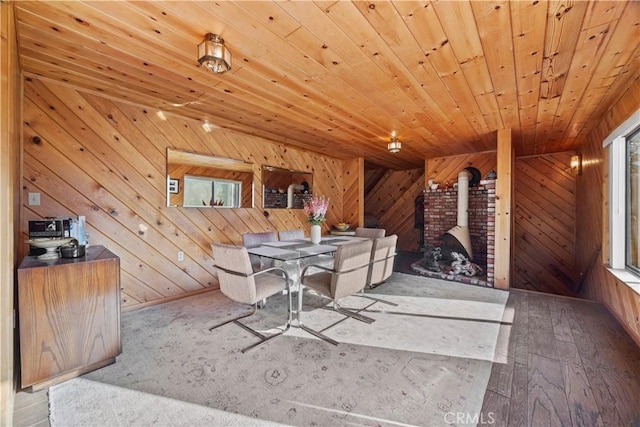 unfurnished dining area with a wood stove, wooden walls, and wood ceiling