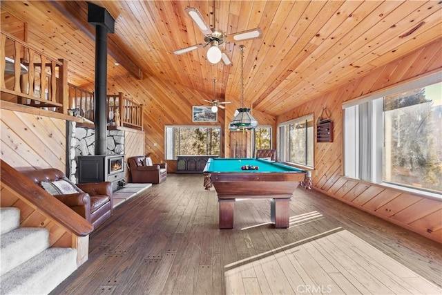 game room featuring vaulted ceiling, a wood stove, dark hardwood / wood-style flooring, and wood walls