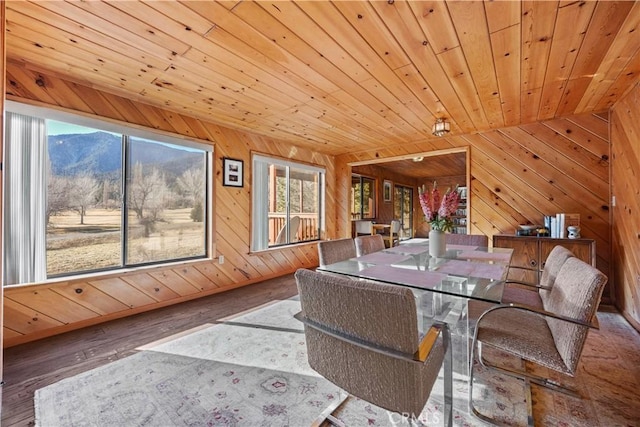 dining space with wood-type flooring, wood ceiling, and wood walls