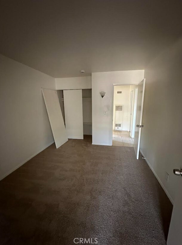 unfurnished bedroom featuring dark carpet and a closet