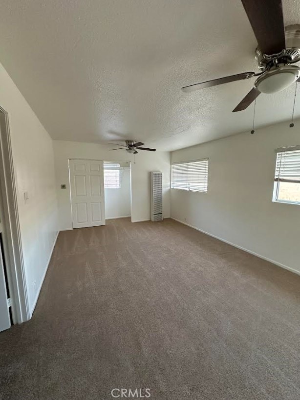 carpeted spare room with ceiling fan and a textured ceiling