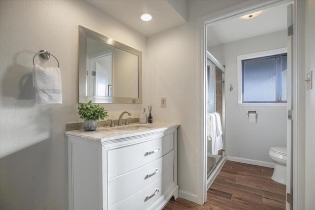 bathroom with vanity, hardwood / wood-style floors, a shower with shower door, and toilet