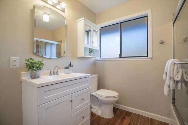 full bathroom with hardwood / wood-style flooring, vanity, bath / shower combo with glass door, and toilet