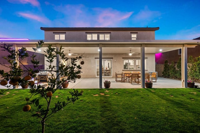 back house at dusk with a lawn, a patio area, ceiling fan, and french doors